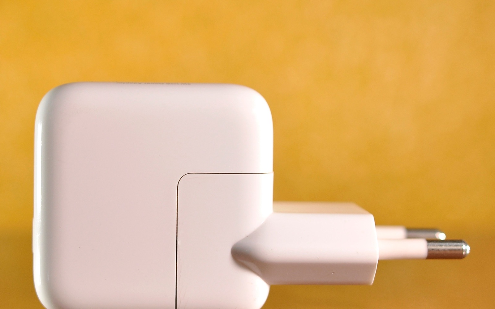 White power adapter against a yellow background, used as an editorial illustration for IECEE CB certificate checks.
