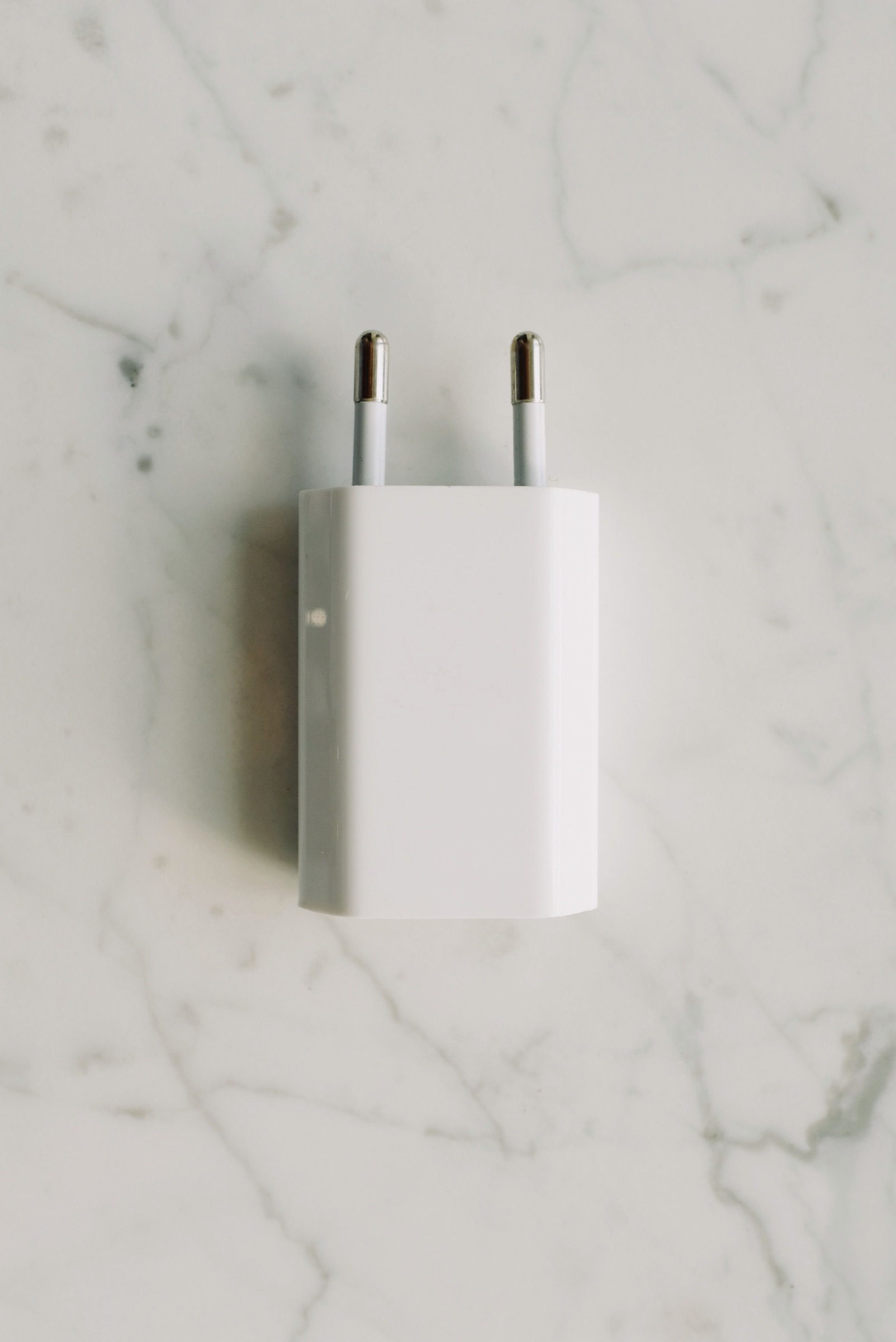 White two-pin power adapter on a marble surface, used as an editorial illustration for China CCC certificate checks.