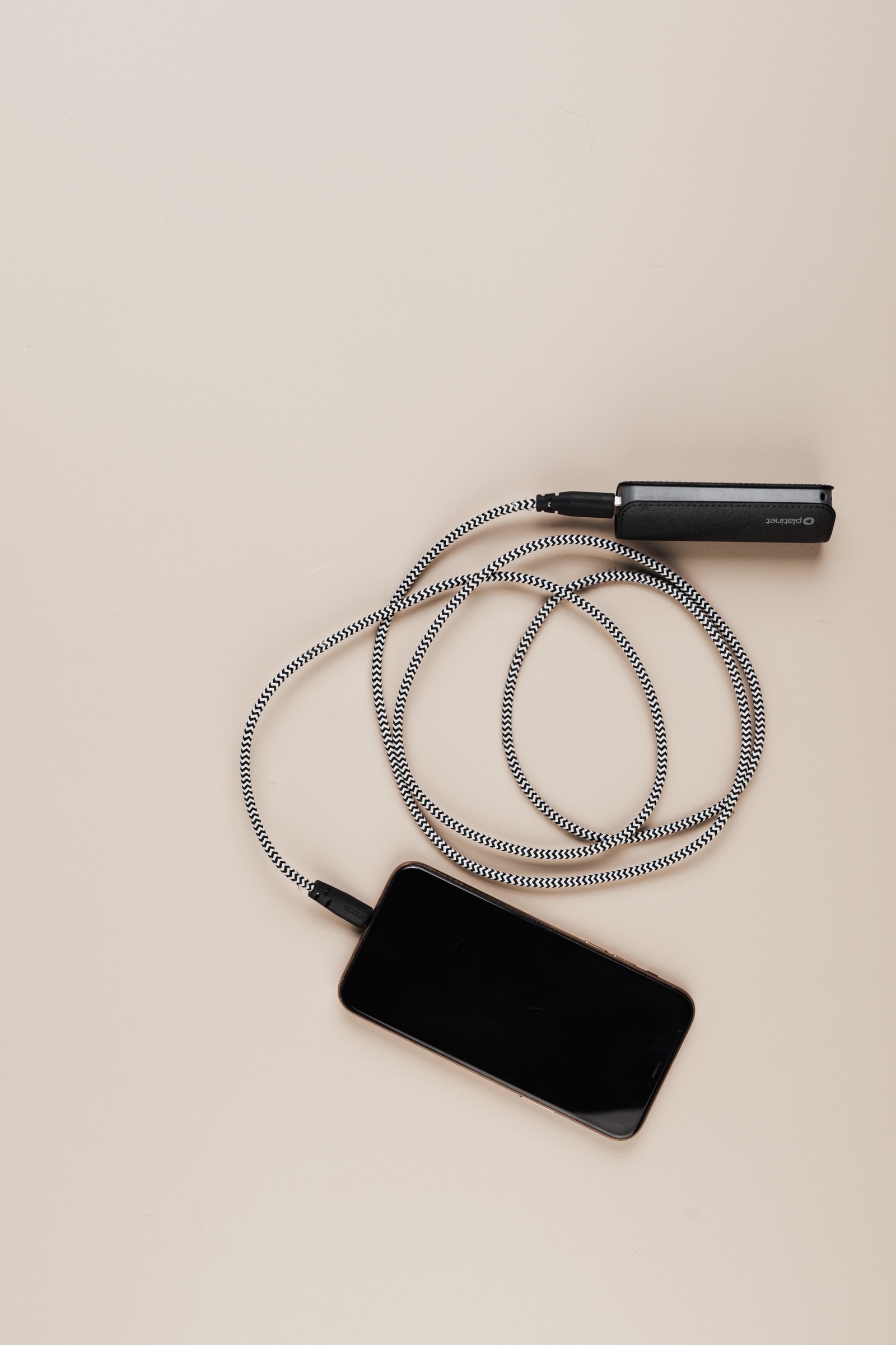 A smartphone connected by cable to a portable power bank, used as an editorial illustration for EU battery-passport checks.