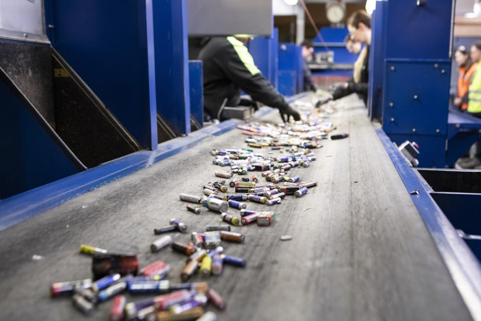 Workers sorting used household batteries on a conveyor at the BEBAT recycling plant in Belgium.