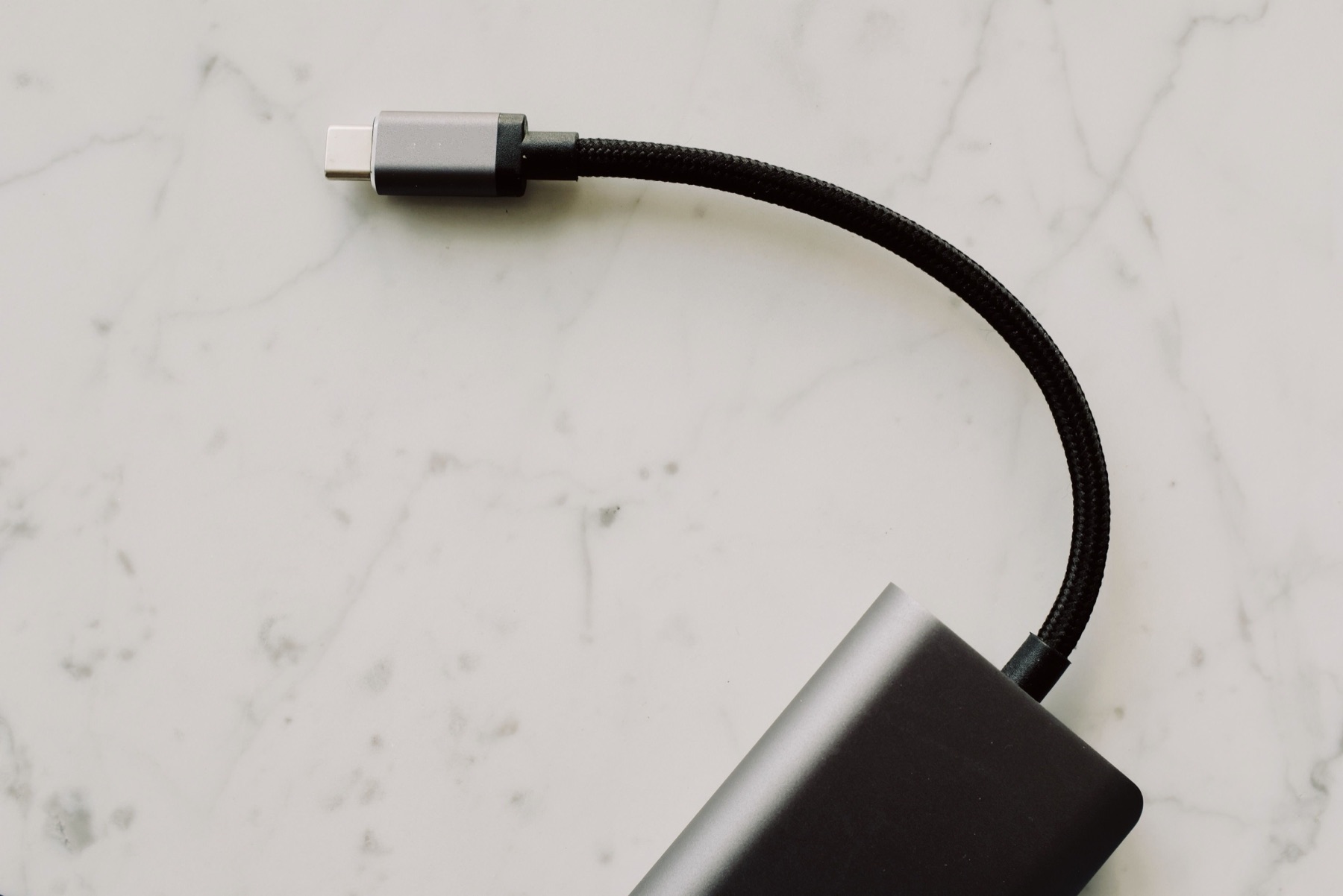 USB-C connector and cable beside an adapter on a marble surface, used as an editorial illustration for EU common-charger checks.