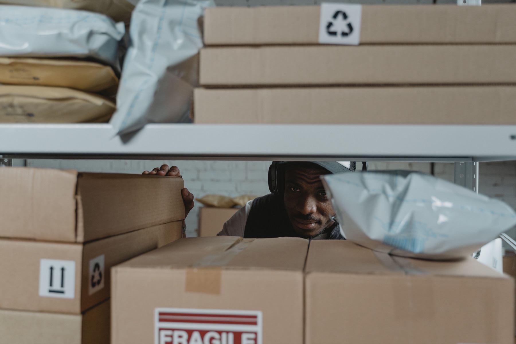 Warehouse worker inspecting parcels on storage shelves, used as an editorial photograph for EU e-commerce customs reform.