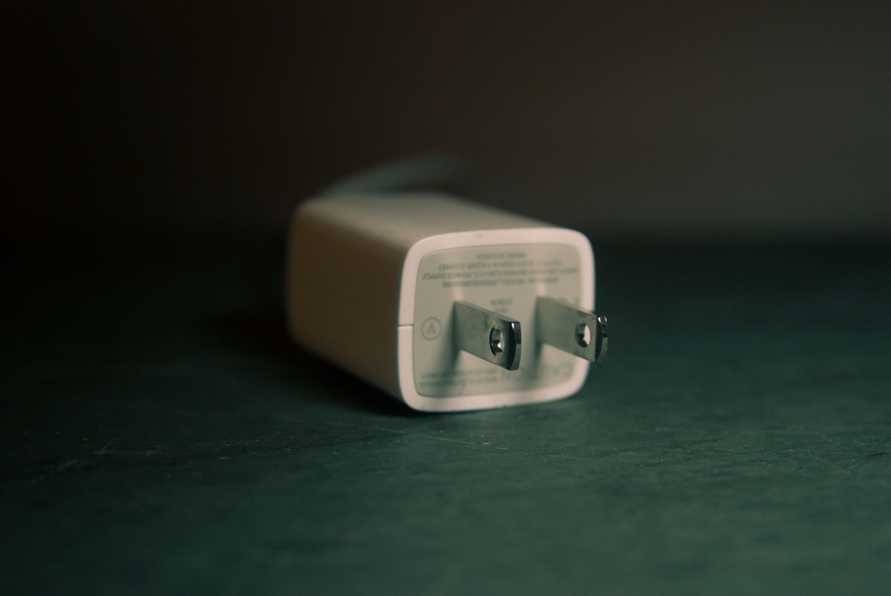 A compact plug-in AC adapter photographed on a dark surface, used as an editorial illustration for Japan PSE document checks.