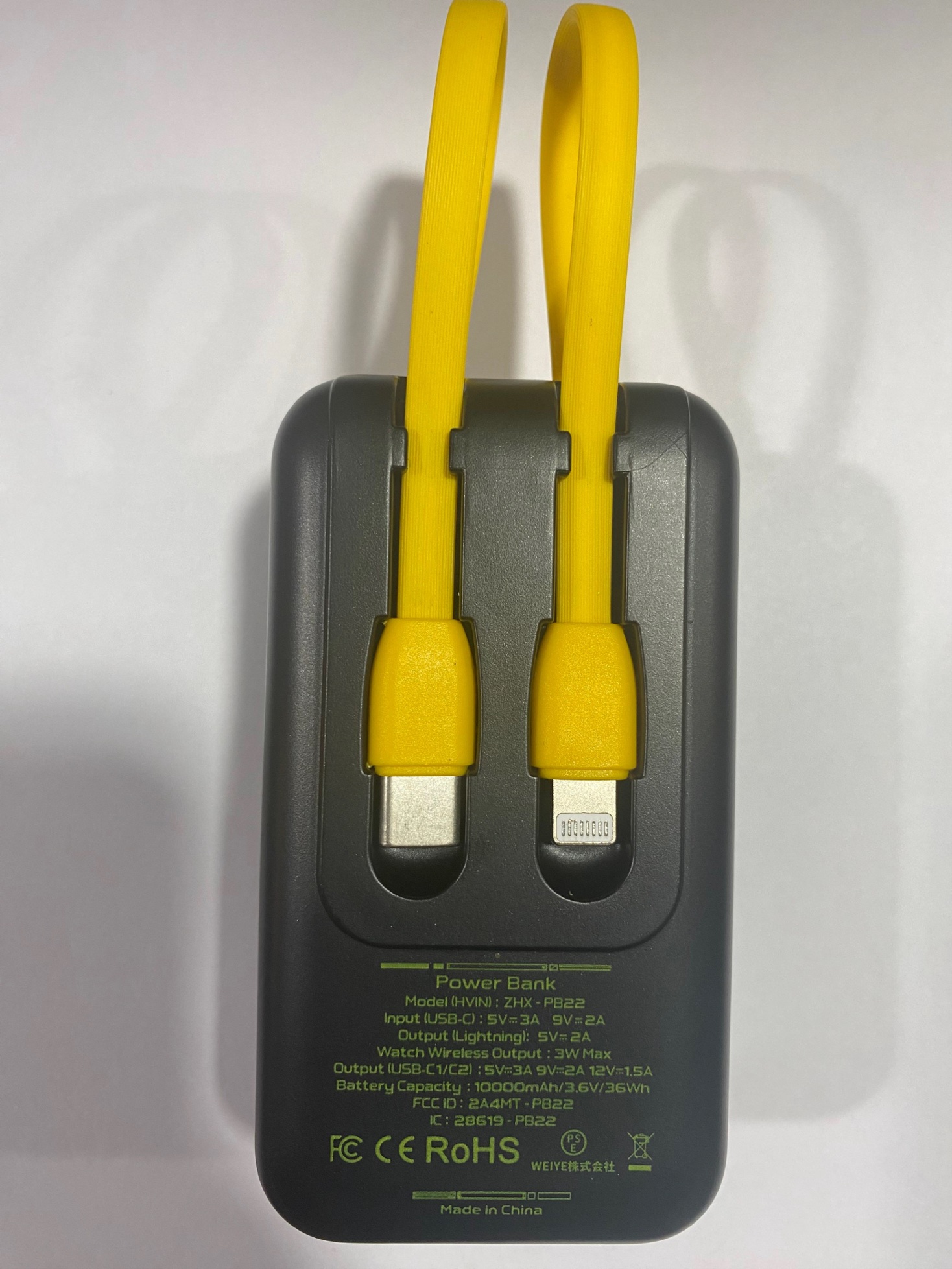 Back of the recalled black NEWDERY power bank, with yellow built-in cables and model ZHX-PB22 printed on its label.