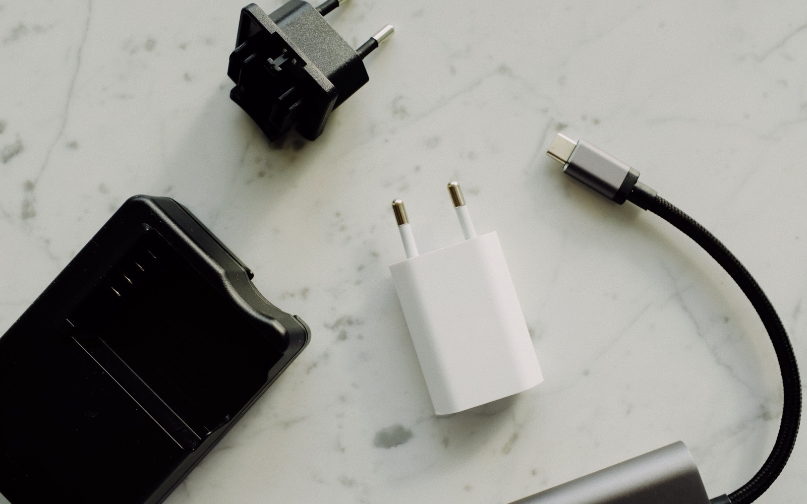 Power adapters and a USB-C cable on a marble surface, used as an editorial illustration for EU Safety Gate checks.