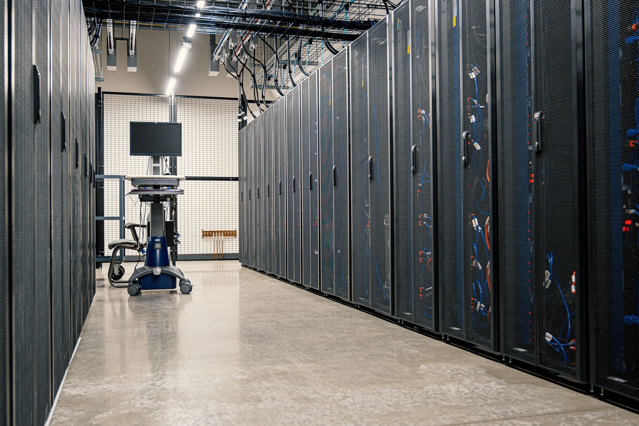 A corridor of server racks in a modern data center, shown as an editorial illustration of the setting discussed.