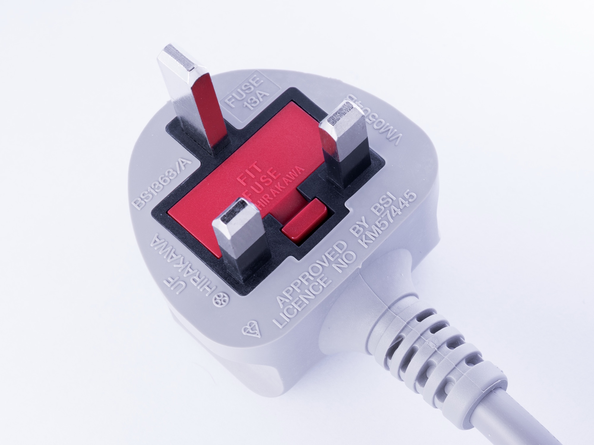 Close-up photograph of a white and red British BS 1363 three-pin mains plug on a pale background.