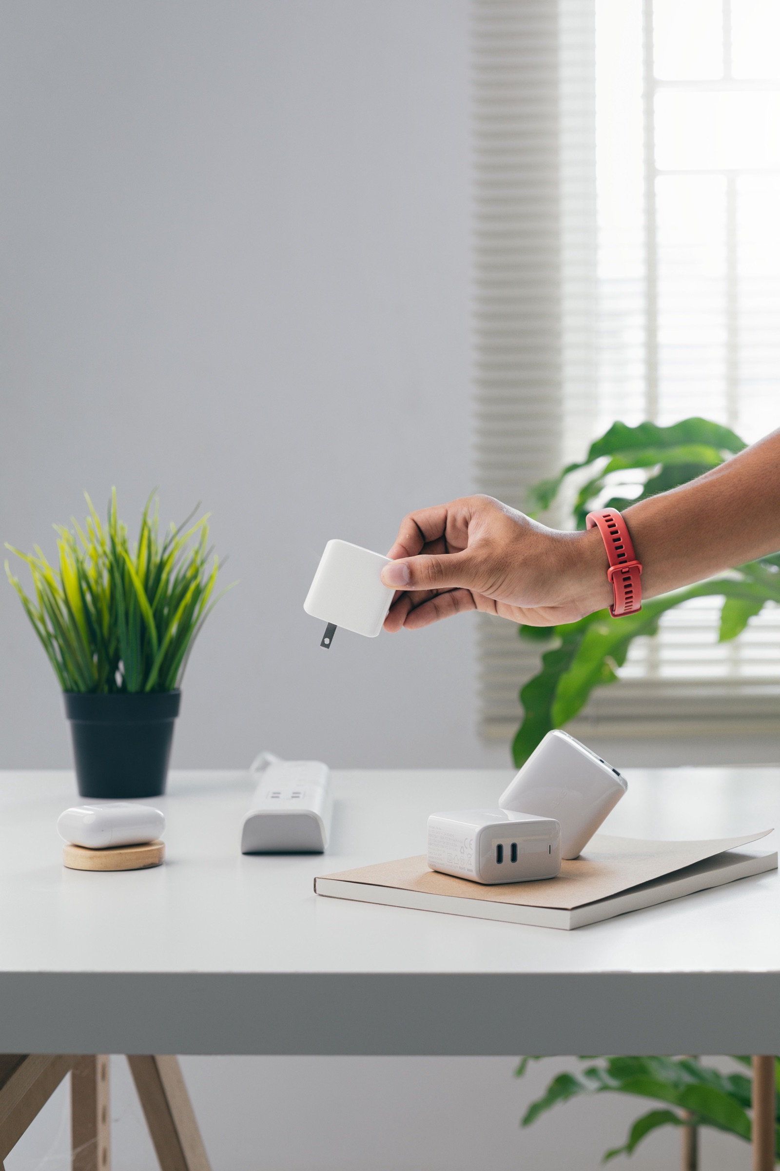A person holding a white plug-in power adapter above a desk with several chargers, used as an editorial illustration for U.S. DOE Level VI evidence checks.